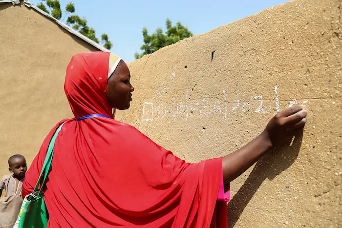 A member of a team of UNICEF volunteer records data in chalk on a wall noting polio immunizations conducted in Borno State, Nigeria in October, 2016. 