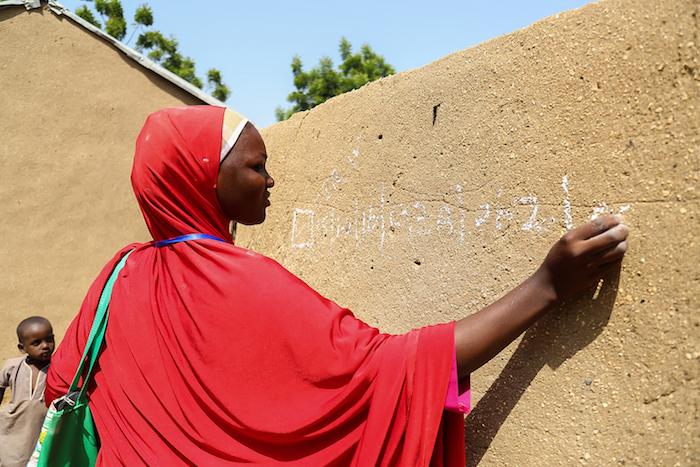 A member of a team of UNICEF volunteer records data in chalk on a wall noting polio immunizations conducted in Borno State, Nigeria in October, 2016. 