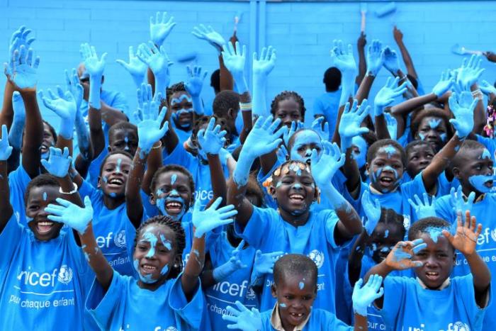Children in Sakassou, Côte d'Ivoire, paint their new school, made out of recycled plastic bricks, blue to celebrate World Children's Day.
