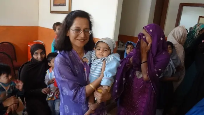 Alina A. Visram, Manager of the Pakistan National PolioPlus Committee, holds a vaccinated child at a health camp in Karachi in 2017. 