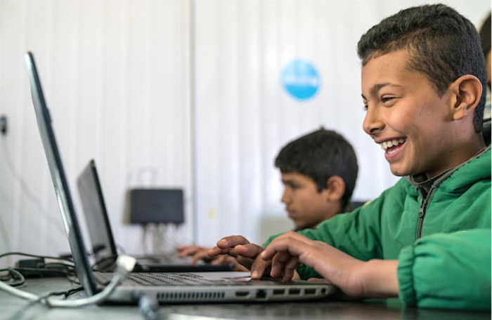 Bashar, 11, a Syrian child refugee living in the Za’atari Refugee camp in Jordan, uses a laptop in an educational program like those supported by the UNICEF USA Bridge Fund.