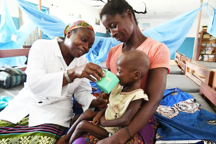 At a UNICEF-supported health center in the village of Zouan Hounien in northwestern Côte d'Ivoire, nurse Blandine Tonga helps a 32-year-old grandmother feed therapeutic milk formula to 3-year-old Doris, who is dehydrated and severely malnourished. At a UNICEF-supported health center in the village of Zouan Hounien in northwestern Côte d'Ivoire, nurse Blandine Tonga helps a 32-year-old grandmother feed therapeutic milk formula to 3-year-old Doris, who is dehydrated and severely malnourished.