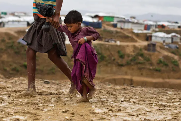 Rumana, 2, is led by a community worker as she and her family are relocated to a safer, new extension area of the Kutupalong-Balukhali camp for Rohingya refugees in Cox's Bazar, Bangladesh in June 2018. UNICEF, Rohingya, monsoon, climate change, Bangladesh, refugees