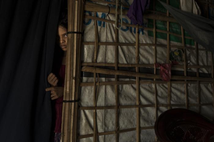 A young Rohingya Muslim girl, peers from behind a curtain in her family shelter in the Bulankuli refugee camp, Cox's Bazar, Bangladesh on 22 July, 2018.
