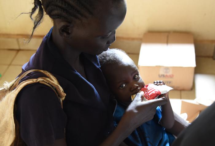 At Rumbek Hospital. Ayen Kuac is helping her daughter Yar Makoi with the appetite test. The test helps the health workers determine how severe the malnutrition is. Yar Makoi is seventh months old and Ayen’s number six. Ayen explains how she has breastfed 