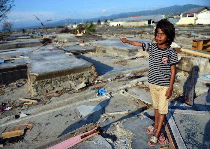 In Talise village, Palu, Indonesia, 9-year-old Tasya points to the ruins of her home, destroyed by the 2018 earthquake and tsunami. 