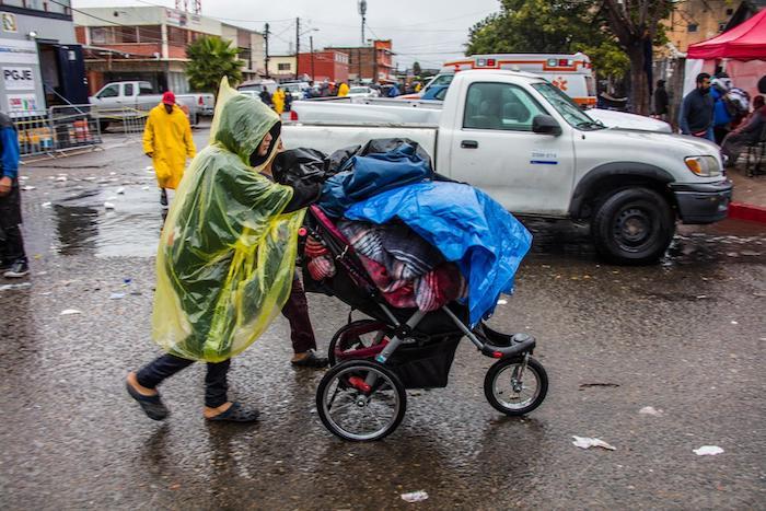 A family migrating from Central America to the U.S. leaves a makeshift shelter during a rain storm in Tijuana, Mexico.
