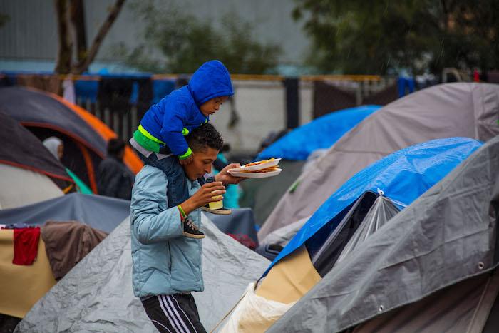 A father and his child walk through a tent city serving as a temporary shelter for migrants in Tijuana, Mexico.