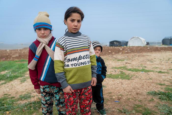 From left: Syrian refugees Yasmeen, 8, Zainab, 9, and Mohammad, 3, wear warm winter clothes they received from UNICEF and partner Mateen in Jordan. 