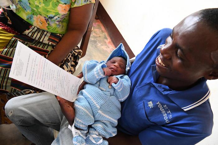 A father holds his newborn baby daughter and her newly issued birth certificate at the UNICEF-supported hospital in Sibiti, in the south of Congo, on February 20, 2019. 