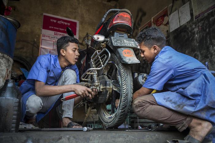 In February 2019 in Bangladesh, 18-year-olds Mohammed (left) and Biplob work on a motorbike as part of a UNICEF-supported vocational training program in Court Bazar, in the Cox's Bazar district.