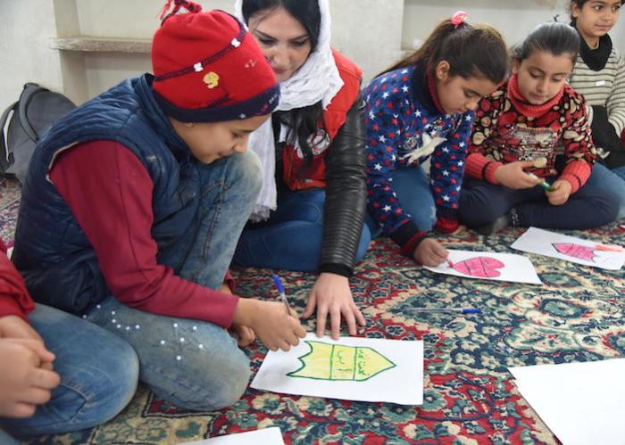 Bajan, 10, (in red hat) draws with friends at a UNICEF-supported primary school in Aleppo, Syria in 2019.