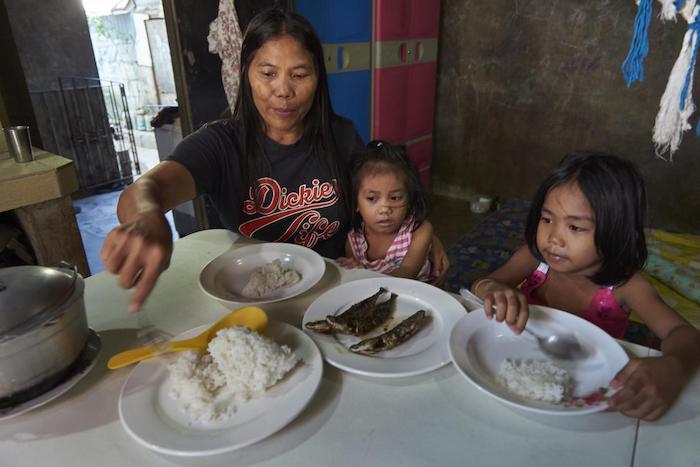 Shirly Mendez feeds her youngest daughter Anika and her granddaughter (right) in her house in Taguig City, the Philippines.