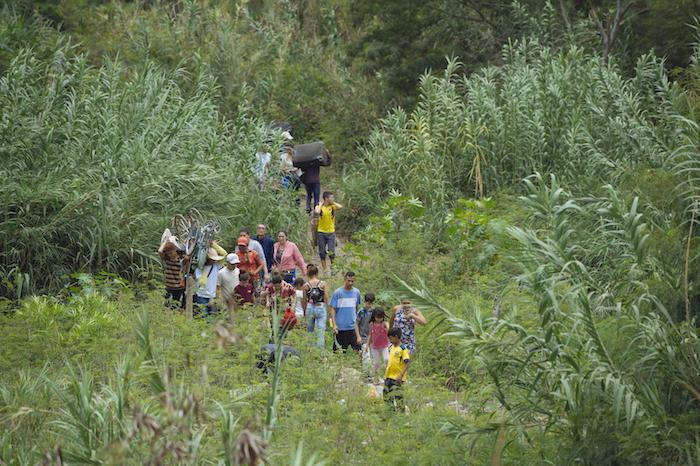 On April 23, 20109 in Cucuta, Colombia, a group of migrants crosses an illegal path next to the bridge connecting Colombia and Venezuela. 