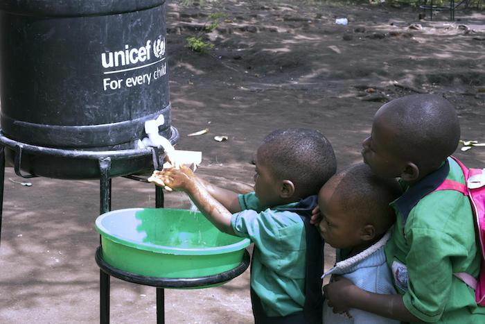 In 2019, pupils at Nyabugando Parents Primary School near the Uganda-DRC border wash as part of the response to the Ebola outbreak, supported by UNICEF and other aid agencies including WHO and the Ugandan government. 