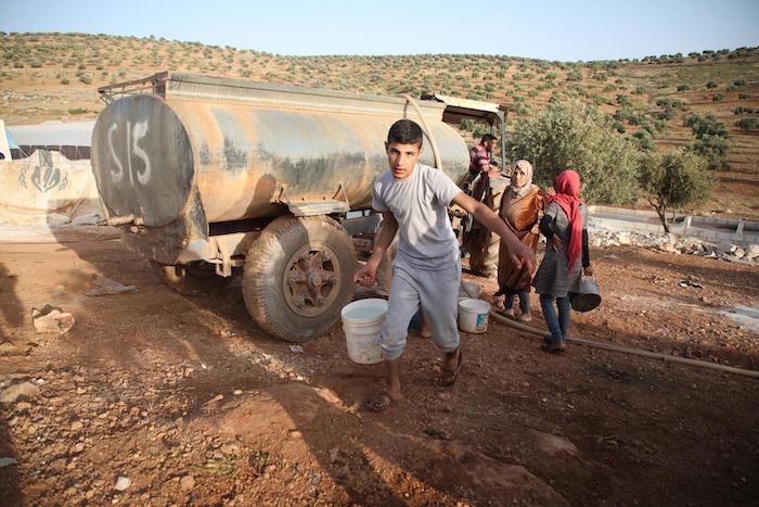 On 3 June 2019 in the Syrian Arab Republic, families fleeing hostilities in Idlib set-up a makeshift camp in Aqrabat village near the Turkish border. A UNICEF-supported water tanker provides clean water to displaced persons.
