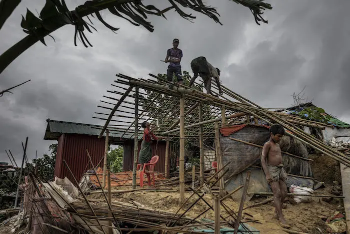 On July 7, 2019 in Bangladesh, men rebuild a house that was destroyed the night before by strong winds in Camp 18, part of the Kutapalong refugee camp in Cox's Bazar. 