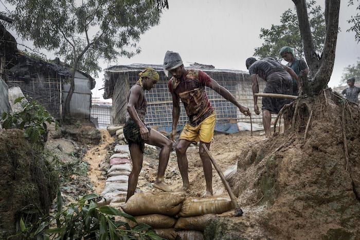 On 6 July 2019 in Bangladesh, two men re-inforce a mountain side path in a flooded Rohingya camp in Cox's Bazar.