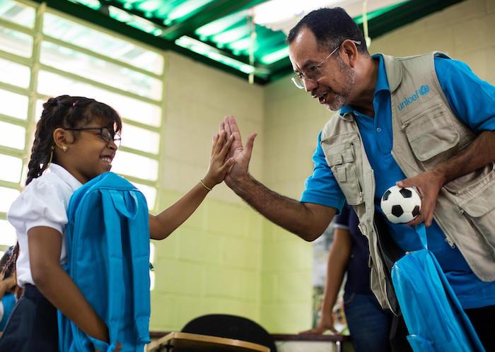 UNICEF Education Officer Dario Moreno high-fives Yeiberling, 9, after giving her a Back-to-School kit in Baruta, Venezuela in September 2019.