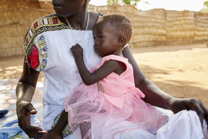 Suffering from severe acute malnutrition, 14-month-old Adut sits on her mother's lap at the UNICEF-supported Gabat nutrition center in Aweil, South Sudan, May 2019. 
