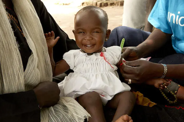 UNICEF nutritionist Jesca Wude Murye measures 11-month-old Amira's mid-upper arm circumference at Gabat nutrition center in Aweil, South Sudan, July 2019.