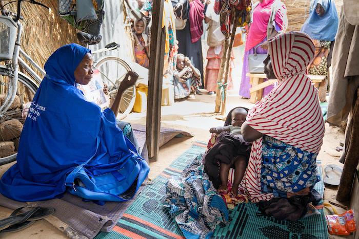 At the Gubio displacement camp in Borno State, Nigeria, a Volunteer Community Mobilizer speaks to a mother about the importance of immunizing her infant son against polio.