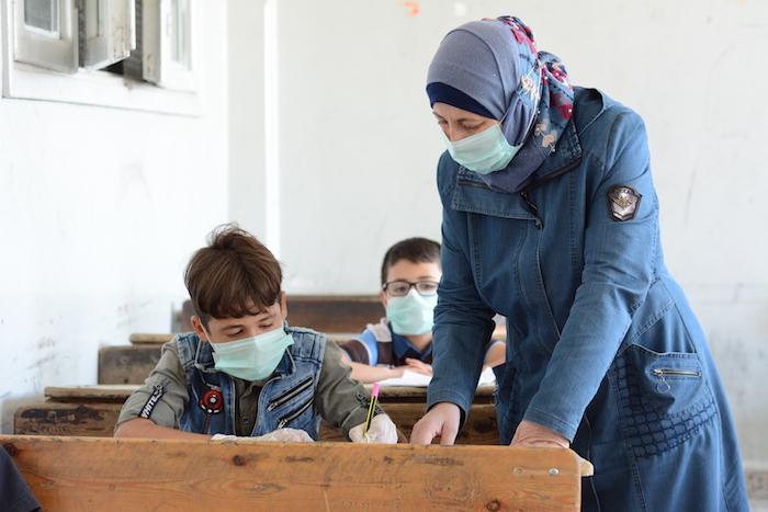 Najwa Almasri, principal of Adnan Almalki school in Hama city, helps a student during a UNICEF-supported ‘Curriculum B’ class, part of an accelerated learning program to help out-of-school kids catch up to peers..