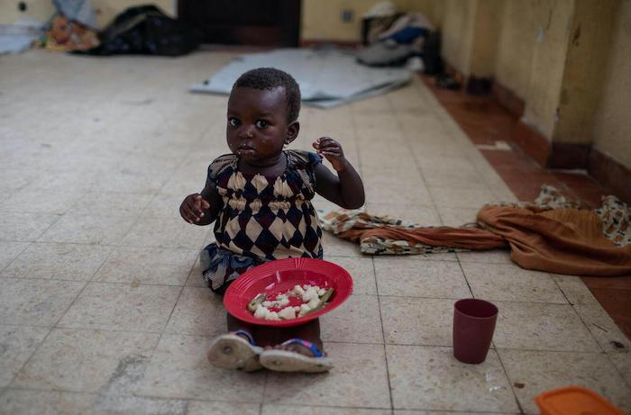 A girl sheltering in a school in Beira, Mozambique, during Cyclone Eloise receives food from emergency responders.