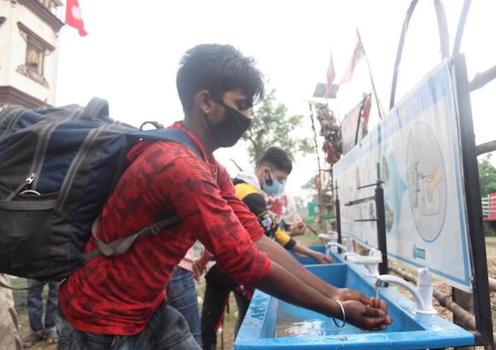 On May 5, 2021, travelers crossing from India to Nepal at the Birguni point of entry in southern Nepal's Parsa district wash their hands and receive temperature checks and antigen tests.