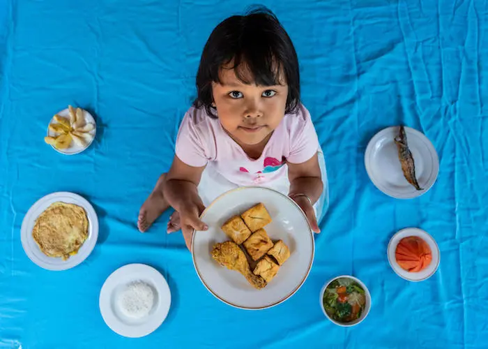 Helga, 5, holds a plate of fried chicken and tofu at her home in Pandes Village, Klaten, Central Java Province, Indonesia on September 7, 2021. Helga, 5, holds a plate of fried chicken and tofu at her home in Pandes Village, Klaten, Central Java Province, Indonesia on September 7, 2021.