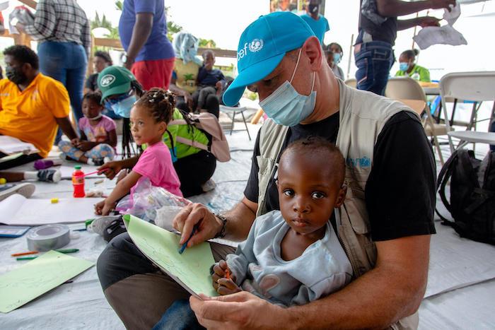 Laurent Duvilier, UNICEF Regional Chief of Communication in Latin America and the Caribbean, draws with 2-year-old Safmi upon her arrival from the U.S. border to Port-au-Prince Airport in Haiti.