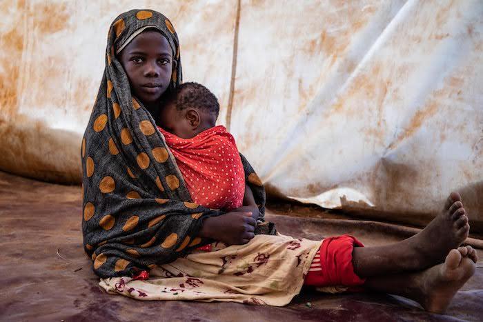 A young girl cradles her infant sibling inside a UNICEF Child-Friendly Space set up to support children displaced by drought in the Somali region of Ethiopia.