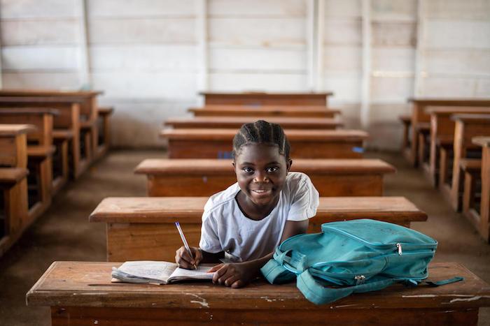 Ten-year-old girl smiles in her new classroom after her old one was destroyed in the Demcratic Republic of Congo.