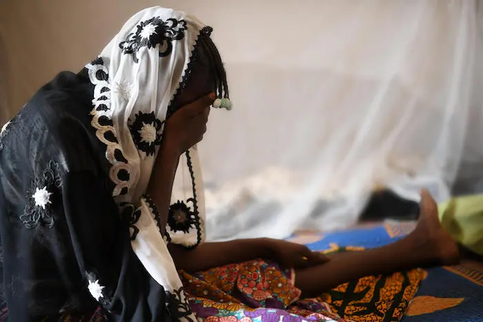 Women in Burkina Faso covering her face with her hands Women in Burkina Faso covering her face with her hands