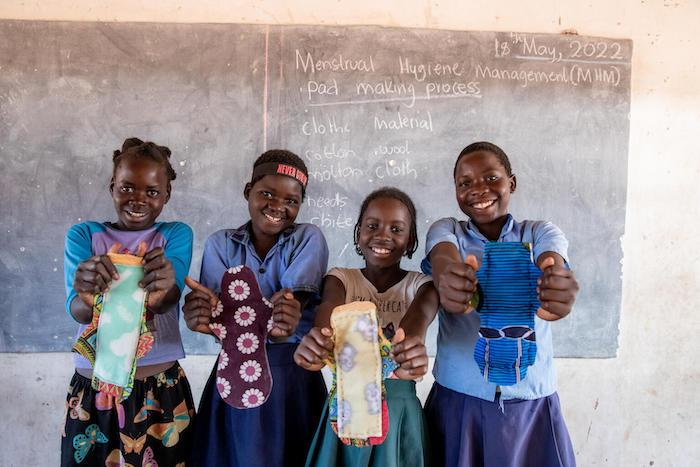 Four teenagers hold up menstrual pads they made during a workshop on menstrual education