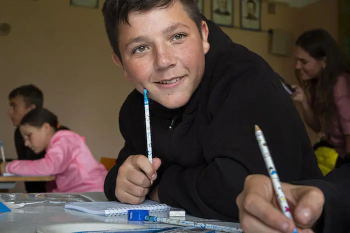Thirteen-year-old boy sits with other students in a classroom of their severely damaged school in the village of Olyzarivka, Ukraine Thirteen-year-old boy sits with other students in a classroom of their severely damaged school in the village of Olyzarivka, Ukraine
