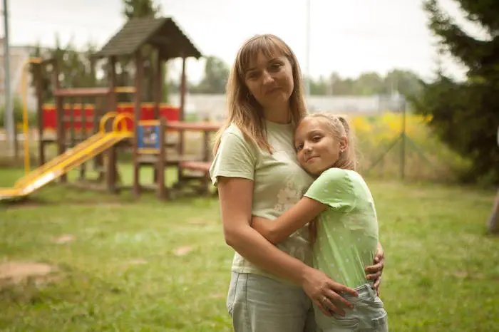 Daughter and mother hug each other while standing near a playground next to their temporary apartment in Krakow, Poland. Daughter and mother hug each other while standing near a playground next to their temporary apartment in Krakow, Poland.