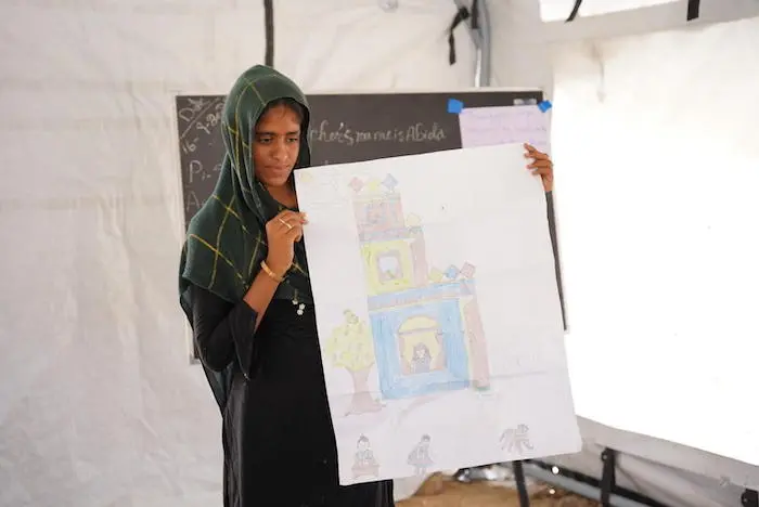 At a UNICEF temporary learning center in near Moenjodaro in Sindh Province’s Larkana District, 17-year-old Kulsoom shows a drawing of the ancestral family home, built by her great-grandfather, that was destroyed by the super floods of 2022. At a UNICEF temporary learning center in near Moenjodaro in Sindh Province’s Larkana District, 17-year-old Kulsoom shows a drawing of the ancestral family home, built by her great-grandfather, that was destroyed by the super floods of 2022.