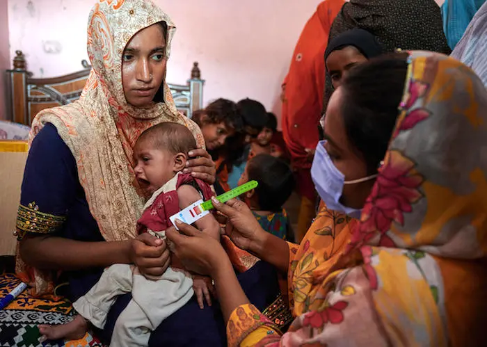 A trained health worker screens a young child for malnutrition at a UNICEF-supported Mobile Health Unit for flood-affected communities in Jano Lander village, Shangar district, Sindh Province. Pakistan. A trained health worker screens a young child for malnutrition at a UNICEF-supported Mobile Health Unit for flood-affected communities in Jano Lander village, Shangar district, Sindh Province. Pakistan.