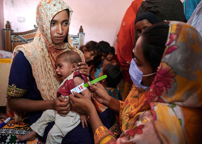 A trained health worker screens a young child for malnutrition at a UNICEF-supported Mobile Health Unit for flood-affected communities in Jano Lander village, Shangar district, Sindh Province. Pakistan. 