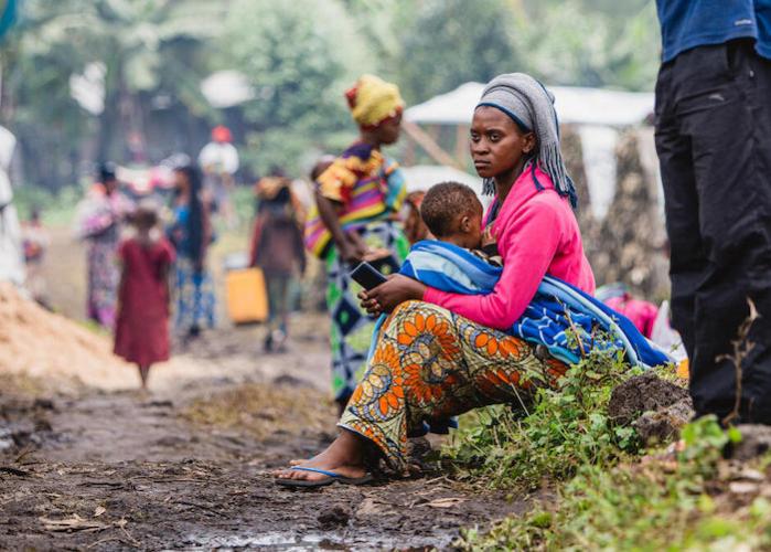 A mother and her child, displaced by recent clashes in Rutshuru, sit on the side of the road in Kibati, North Kivu province, eastern DRC, where UNICEF and partners are distributing emergency supplies.