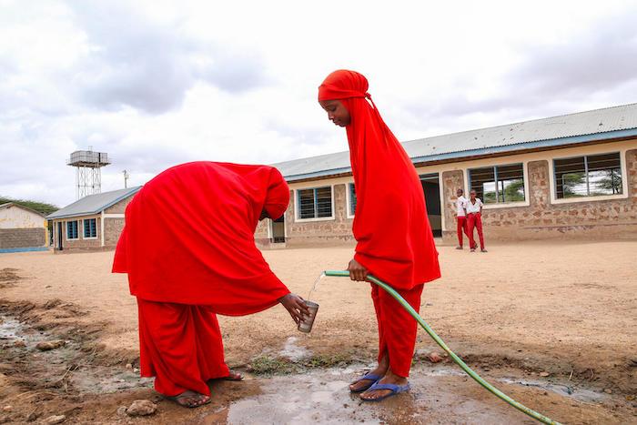 Nasteha, 13, left, and Siham, 13, are able to access safe water from a point outside Daley primary school in Garissa County, Kenya, thanks to a UNICEF-supported solar-powered borehole in the village.. 