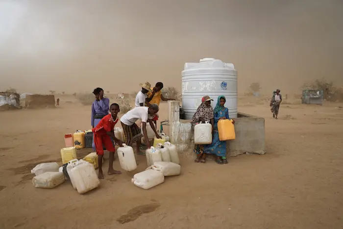 Collecting water as a sandstorm approaches in a settlement for internally displaced persons in Hajjah Governorate, Yemen. Water, carefully rationed, is available during one-hour windows, normally three times a day. © UNICEF/UN073954/Clarke for UNOCHA