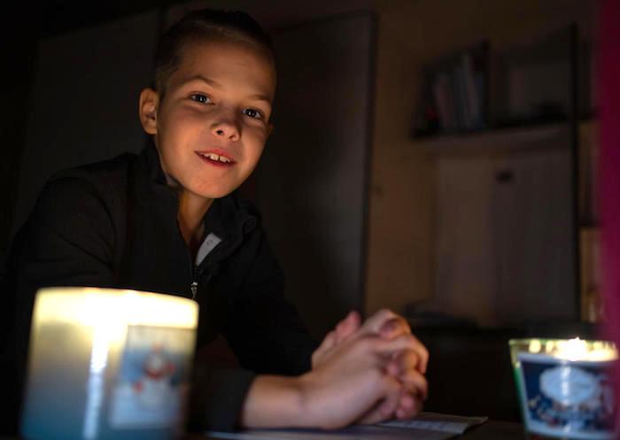 Tymofii, 11, does homework by the flickering light of a candle in Bucha, Ukraine.