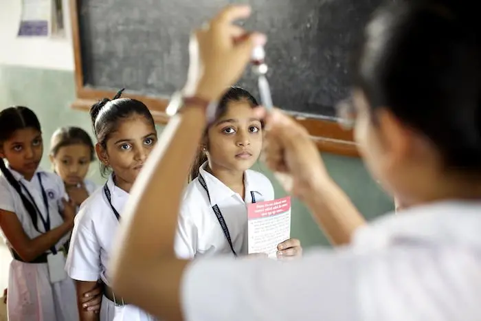 Girls waiting to be immunized watch as a vaccinator fills a syringe with measles vaccine, during an immunization session at Deewan Ballubhai school in Ahemabad, Gujarat state, India. Girls waiting to be immunized watch as a vaccinator fills a syringe with measles vaccine, during an immunization session at Deewan Ballubhai school in Ahemabad, Gujarat state, India.