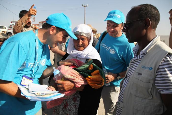 UNICEF workers interact with a 13-day-old Yazidi infant, held by an elderly woman, in the town of Peshkhabour in Dohuk Governorate. 