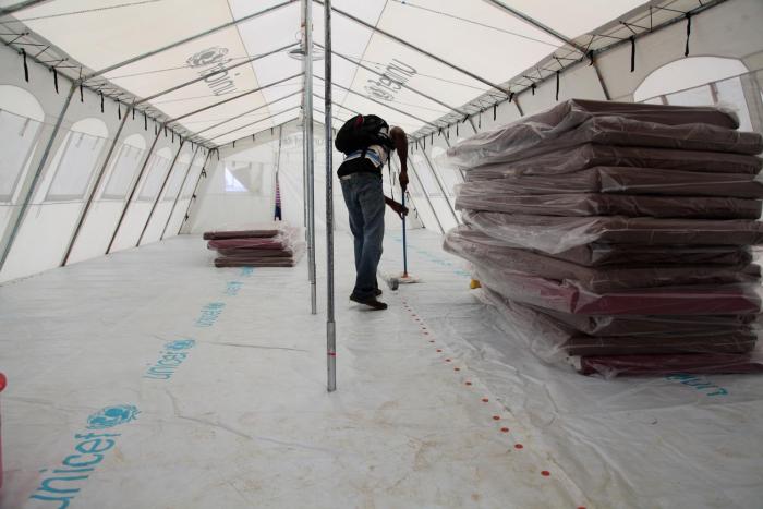 A worker cleans a newly built UNICEF tent at an expanded Ebola treatment center on the outskirts of Monrovia, Liberia. © UNICEF/NYHQ2014-1257/Jallanzo . 