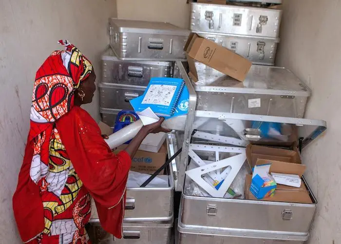 A teacher at a camp in Maiduguri, Nigeria examines educational supplies provided by UNICEF for children displaced by conflict.
