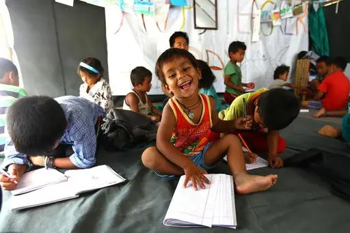 After a 7.8 magnitude earthquake hit Nepal in 2015, around 7,000 people were displaced from their homes. Here, a young child smiles as he works on lessons at the temporary learning center UNICEF set up to help kids keep up with their studies.