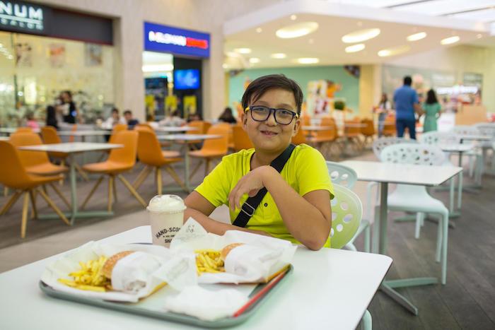 On August 27, 2019 in Almaty, Kazakhstan, 10-year-old Yerzhan poses with his fast food lunch: two hamburgers with french fries and a milkshake. 
